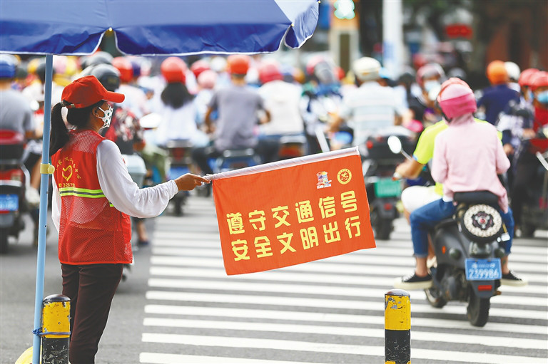 6月15日，在海口海府路与红城湖路延长线交叉路口，志愿者协助交警维护交通秩序。本报记者 张茂 摄