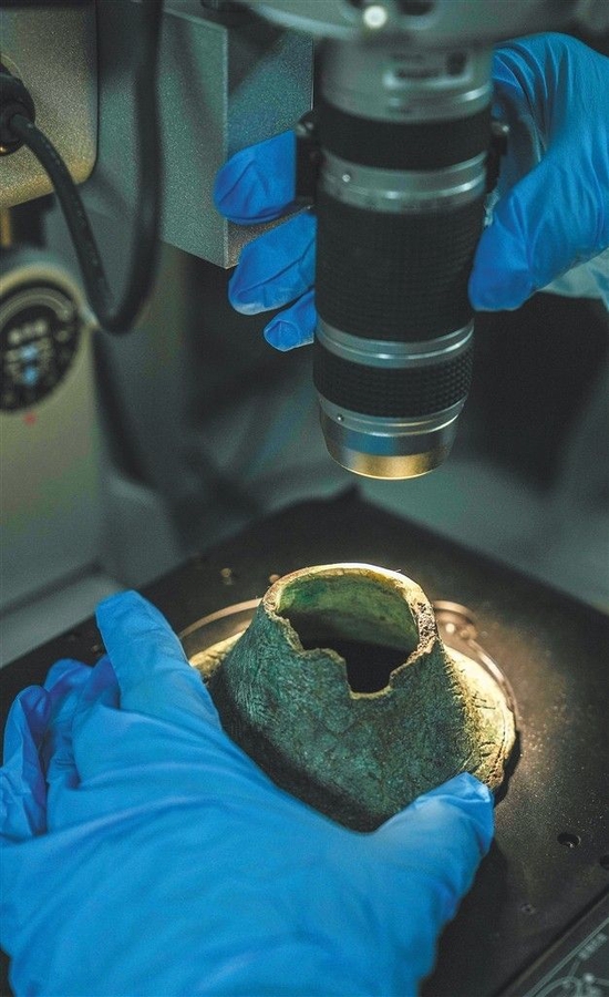 海南省博物馆的文物修复工作人员用超景深显微镜观察铜铃的纹饰及锈蚀物，以便了解其质地、文物病害类型等。