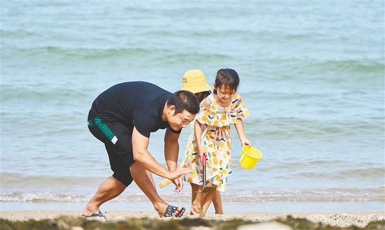 6月5日，在琼海市潭门镇，游客在海边玩耍。本报记者 袁琛 摄