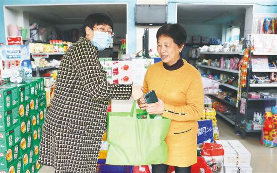 近日,在海口市龙华区翰林西苑小区外的一商店内,社区团购团长刘晓辉将团购的商品交给客户。本报记者 李天平 摄