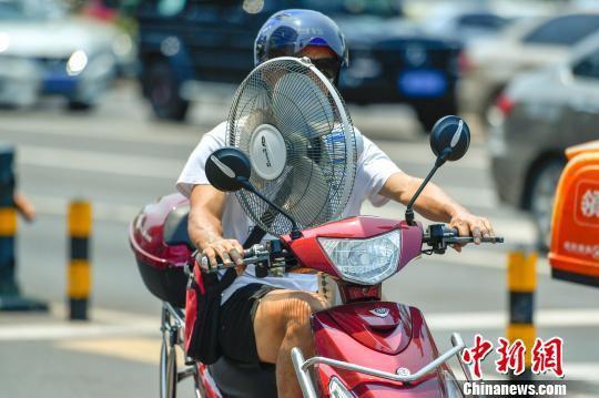 图为海口一民众带着电风扇出行。　骆云飞 摄