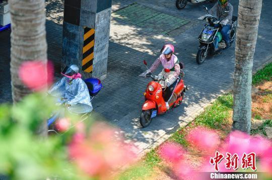 图为海口民众“全副武装”骑电动车出行。　骆云飞 摄