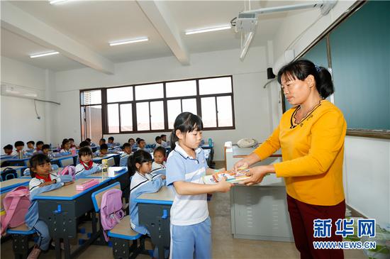 中央民大附中陵水黎安实验小学正式开学，老师给学生们发放课本。新华网发