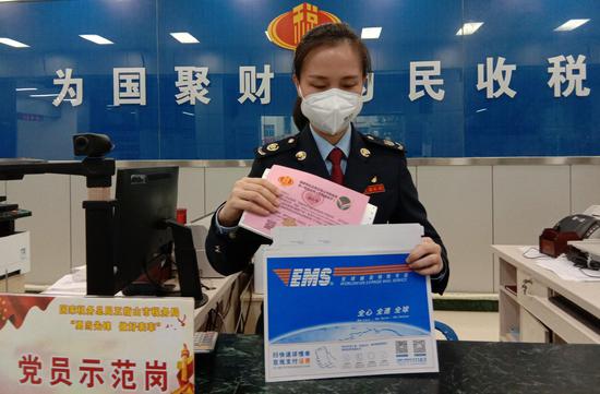 (图2:疫情期间,五指山市税务局提供“网上申领、邮寄配送”发票,图为办税服务厅工作人员邮寄发票,并附上来自五指山市税务局局制作的“连心卡”。)