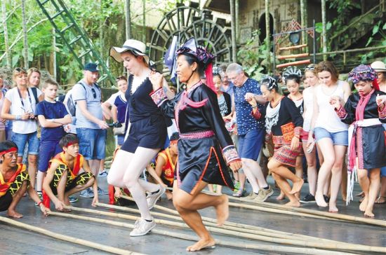 外国游客在槟榔谷景区体验黎族竹竿舞