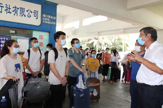 校长林强在海口火车站迎接返校学生,与学生交流