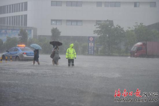 2018年8月10日，暴雨造成海口东的动车站外积水严重，交警在淹没的斑马线旁疏导交通，让刚下车的旅客及时过马路。海南日报记者袁琛 摄