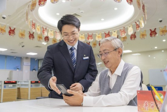 图为建行海南省分行营业部员工为老年客户服务。