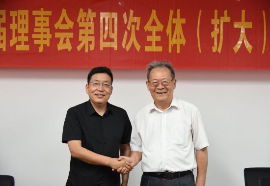 海南省苏学研究会创会理事长李公羽（右）向新任会长甘生统表示祝贺。