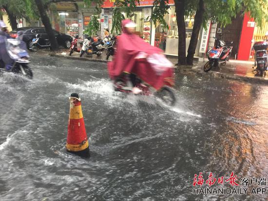 这是海口市金花新路上，大雨造成路面积水现象，不少市民冒雨涉水出行的情景。 海南日报记者张杰 摄