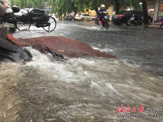 这是海口市金花新路上，大雨造成路面积水现象，不少市民冒雨涉水出行的情景。 海南日报记者张杰 摄