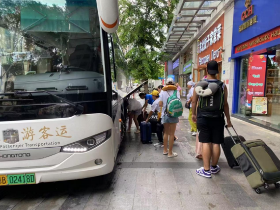 图：游客有序登上大巴车。