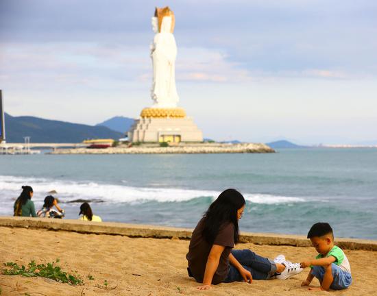 12月17日，游客在三亚南山文化旅游区海边游玩、自拍。