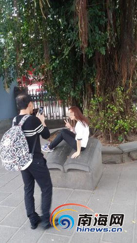 女游客坐在石铭文上拍照。