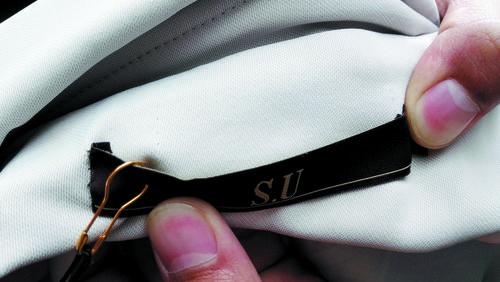 “S.U”牌女装大衣的衣领口处，有扯下标签针线头痕迹。