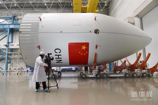4月13日，一名媒体记者在航天科技集团一院天津大运载基地长征五号运载火箭总装车间拍摄长征五号运载火箭顶部的整流罩。 新华社记者 陈晔华 摄