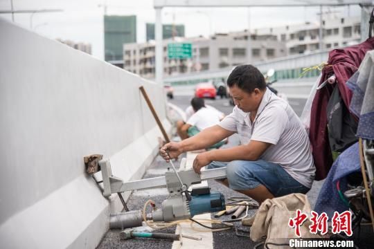 图为19日上午,工人在海秀快速路上钻排水孔。 洪坚鹏 摄