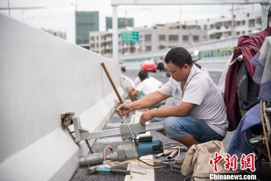 图为19日上午，工人在海秀快速路上钻排水孔。　洪坚鹏 摄