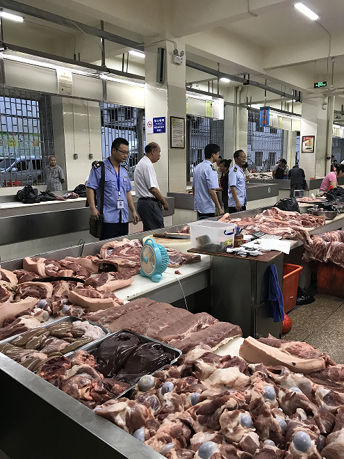 执法人员突击检查农贸市场猪肉摊