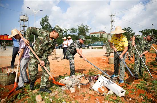 陵水县委书记麦正华与黎安镇的领导干部共同清理着垃圾杂物