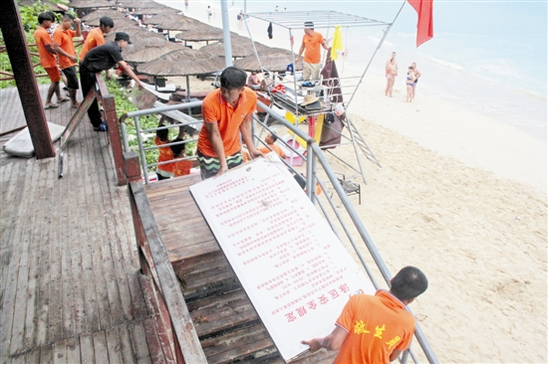 7月23日，大东海景区员工搬离沙滩上旅游设备。为做好防风工作，大东海景区提前做好关闭泳场等工作。本报记者孙清摄