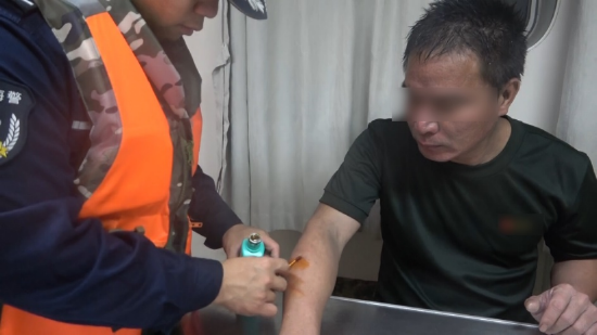 （海警救援人员为获救男子开展初步身体检查并处理伤口）