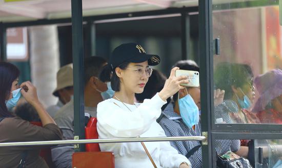 12月18日，一游客在三亚南山文化旅游区乘坐“小火车”游览时自拍。