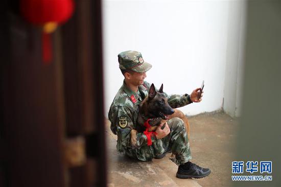 2月9日，警犬训导员关子翰抱着警犬“马博”和家人视频。新华社发（蒋波 摄）