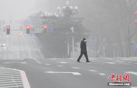 资料图：2月13日，吉林省多地出现大雾，市民戴口罩出行。张瑶 摄