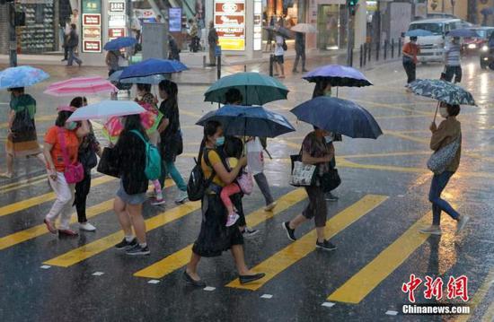 资料图：市民在街头撑伞出行。中新社记者 张炜 摄