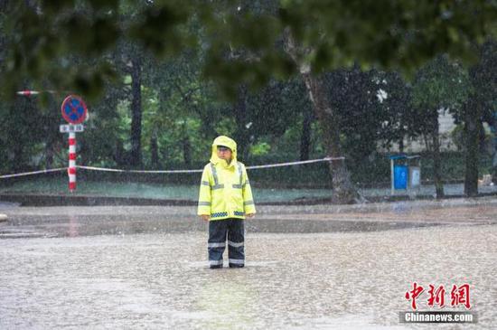 资料图：6月13日，浙江省金华市浦江县大雨倾盆，交警冒雨执勤，阻拦车辆进入漫水路段。 中新社发 张浩钺 摄