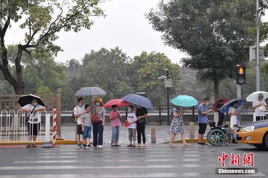 资料图：民众冒雨出行。中新网记者 李骏 摄