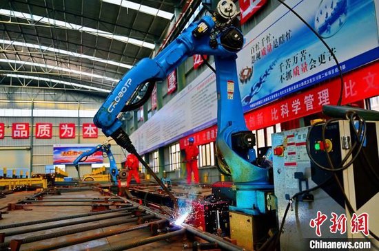 钢筋加工场内的机器人挥舞手臂焊接钢筋。 刘康 摄