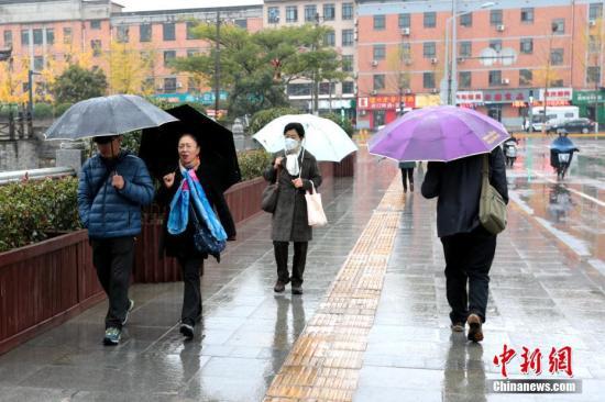 资料图：民众打伞出行。中新社记者 张远 摄