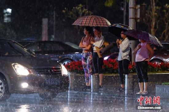 街头行人撑伞挡雨。中新社记者 陈骥旻 摄