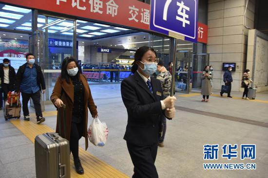 图为8日凌晨,武昌站工作人员引导乘客进站上车。新华网发 陈俊摄