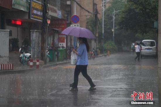 6月18日下午，云南省昆明市突降暴雨，市民冒雨出行。 中新社记者 刘冉阳 摄