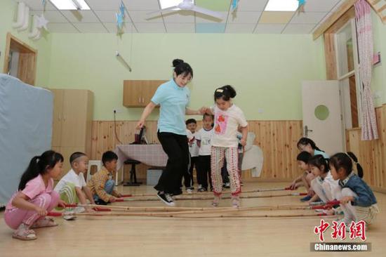 资料图:老师带领孩子们在教室内游戏。中新社记者 张远 摄