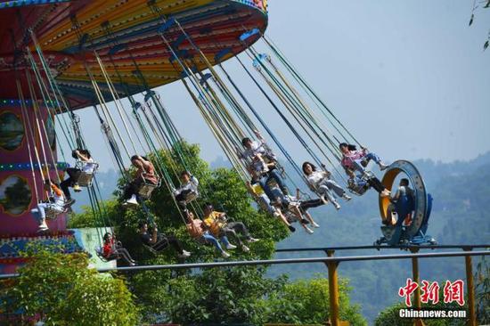 5月1日,“五一”节假的第一天, 重庆涪陵红酒小镇景区内的游客乘坐体验游乐设施。 中新社记者 陈超 摄