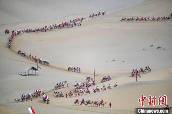 图为今年端午节假期，丝绸之路国际旅游名城甘肃敦煌鸣沙山出现“驼队如龙”景象。　王斌银　摄