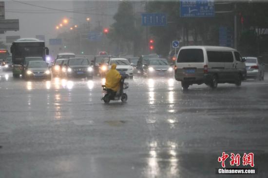 资料图：一名市民穿着雨衣骑车出行。中新社记者 贾天勇 摄