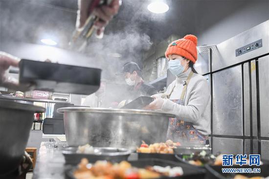 “雨衣妹妹”刘女士在位于武汉光谷青年城的餐饮门店厨房里分装盒饭（2月26日摄）。新华社记者 程敏 摄