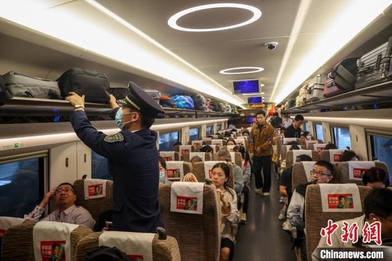 列车乘务长在车厢内整理旅客行李。中新网记者 张畅 摄