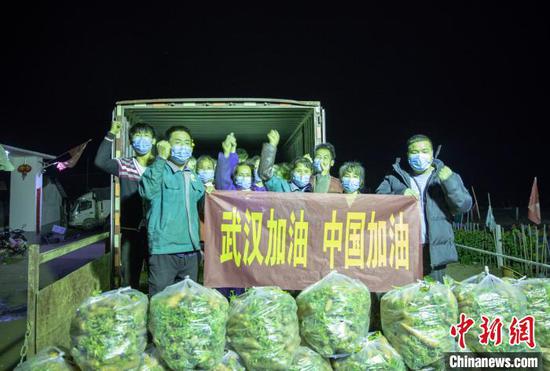 张飞带领着大伙将基地的蔬菜打包装车，并打出“武汉加油，中国加油”的横幅。　张小东 摄