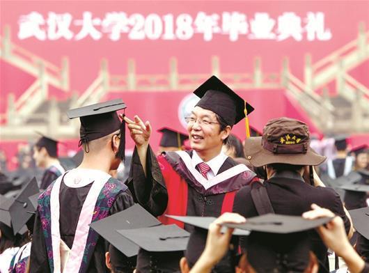 图为：6月22日，导师冒雨给武汉大学毕业生拨穗 楚天都市报记者萧颢宋枕涛摄