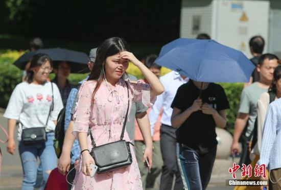 资料图：民众在高温晴晒天气出行。中新社记者 贾天勇 摄