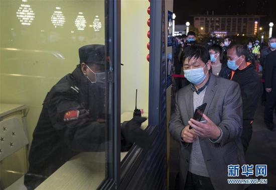 4月7日晚,旅客在武昌火车站向工作人员出示健康码。 新华社记者 费茂华 摄