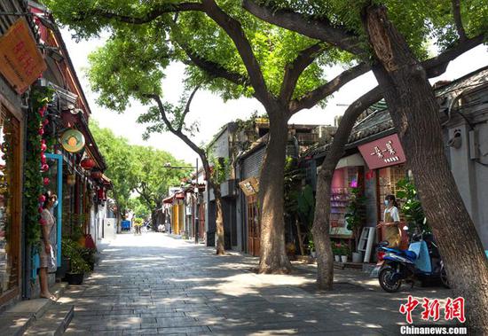 6月18日,南锣鼓巷两家商铺的店员在各自门口隔路聊天。中新网记者 李霈韵 摄