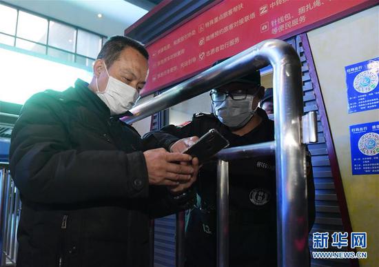 4月8日凌晨，值守在武昌火车站的工作人员协助进站乘客扫描健康码。新华社记者 李贺 摄