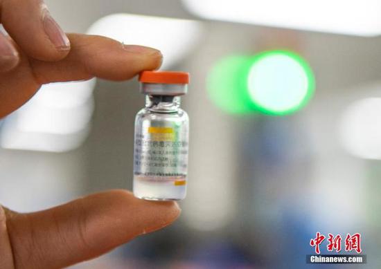 图为2021年1月6日，位于北京市大兴区的北京科兴中维生物技术有限公司的仓库内，工作人员展示一支西林瓶装新冠灭活疫苗。（资料图片） 中新社记者 侯宇 摄